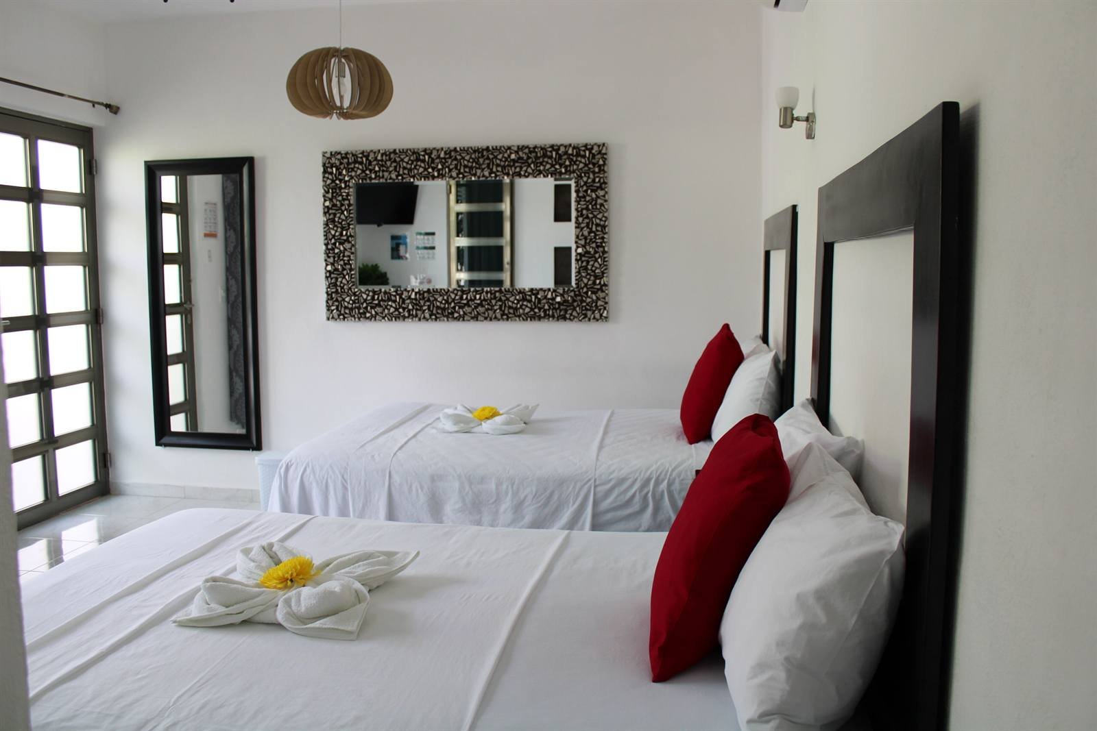 Comfort quadruple room with two double beds and a large framed mirror